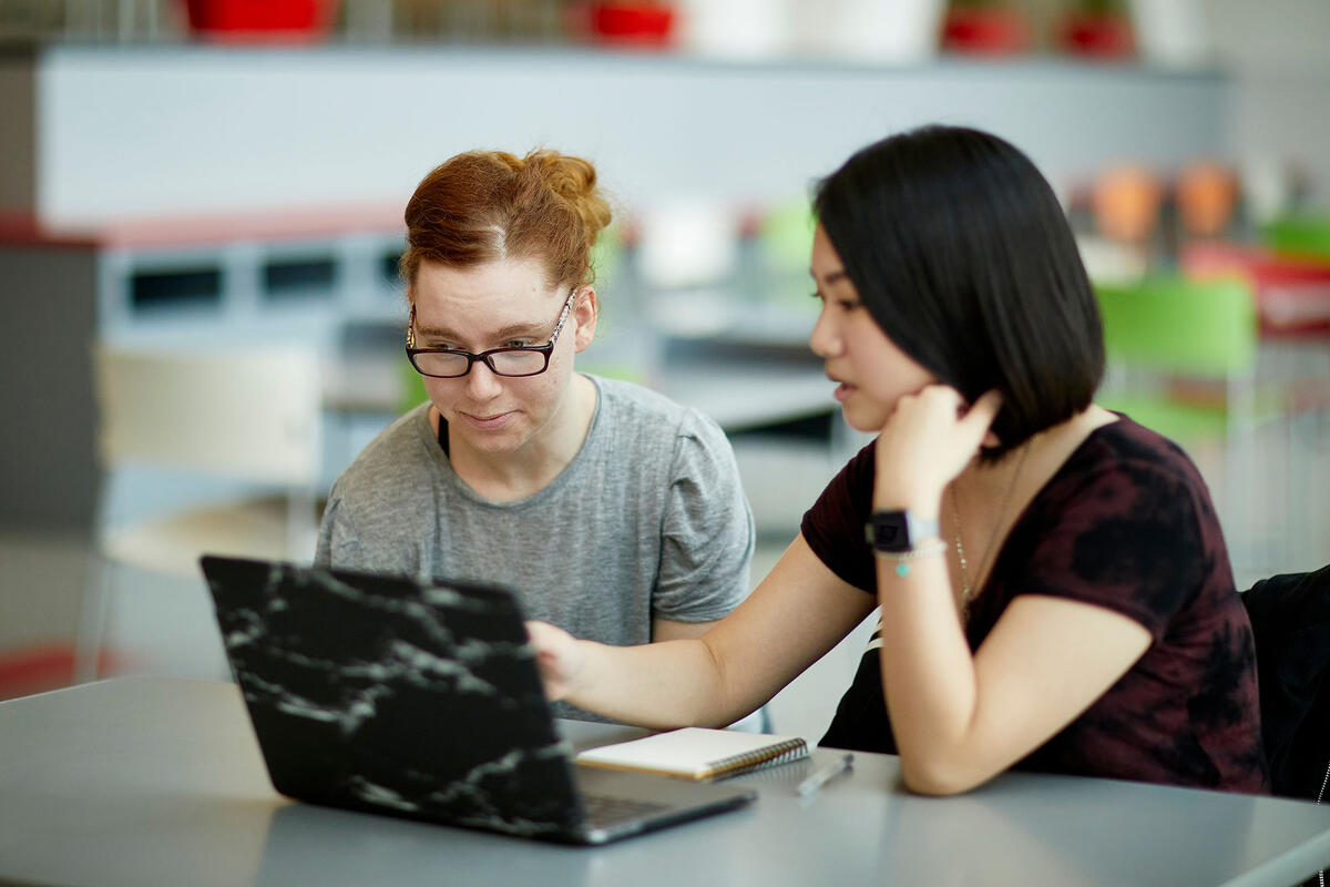 Two women looking at a laptop and talking